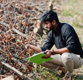 South asian agronomist farmer with clipboard inspecting cut trees in the farm garden. Agriculture production concept.